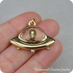 This UFO Charm comes with a gold jump-ring as pictured. Please note that photo is not to scale and may appear larger to show detail. Refer to exact measurements below.Additional attachments (lobster clasp, large-hole bead, necklace chains) are available from the charm-attachments drop-down menu.  For a visual example of the different attachments and what each one is best suited for, scroll through the photos until you see the example photo or visit https://etsy.me/2BY7DAW for detailed informatio Novelty Gold Pendant Jewelry, Novelty Gold Metal Jewelry, Novelty Gold Jewelry Gift, Gold Novelty Round Jewelry, Handmade Gold Novelty Jewelry, Space-themed Gold Jewelry Gift, E.t Movie, Alien Stuff, Alien Gift