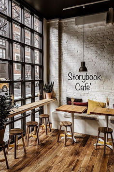 an empty restaurant with wooden tables and chairs in front of large windows that overlook the street