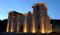 a large stone building with lights on it's sides and windows lit up at night