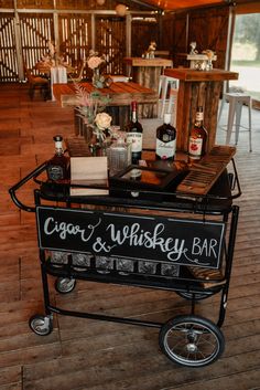 a bar cart sitting on top of a wooden floor next to a table filled with bottles