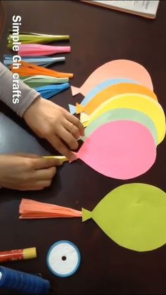 someone is making colorful paper fish out of construction paper and crayons on the table