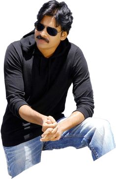 a man in black shirt and sunglasses sitting on a white surface with his hands crossed