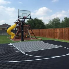 a backyard basketball court with a yellow slide