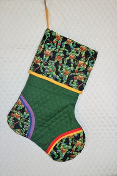 a christmas stocking hanging on a quilted bed with an ornament design