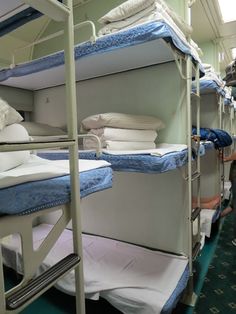 several bunk beds are lined up in a room with green carpet and white sheets on them