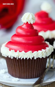 two red cupcakes with white frosting on a plate