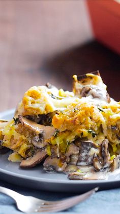 a slice of mushroom and cheese quiche on a blue plate with a fork next to it