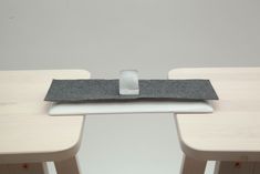 a laptop computer sitting on top of a wooden desk next to two white stools