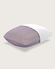 a purple and white pillow sitting on top of a bed