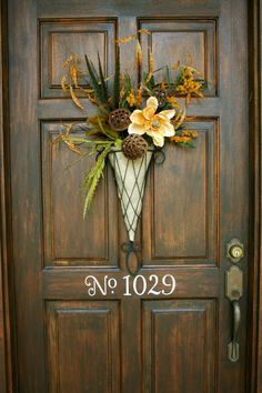 the front door is decorated with flowers and pine cones for fall decorating it says no 1039