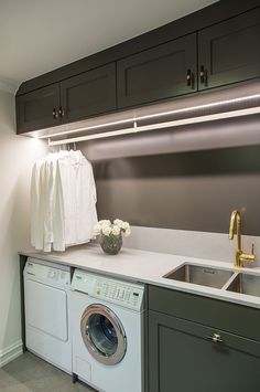 a washer and dryer in a small room with dark wood cabinets on the wall