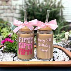 two mason jars decorated with pink bows and happy birthday messages are sitting on a tray