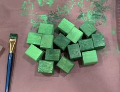 some green cubes and a paintbrush on a table