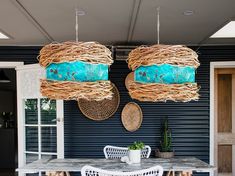 two wicker lamps hanging from the ceiling above a table with chairs and tables in front of it