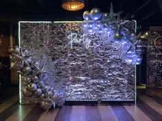 a large piece of art made out of silver foil and balloons on display in a dark room