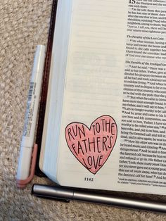 an open book with the words run to the father love written on it and a pen