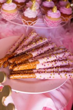 a pink and gold birthday party with cupcakes on the plate, sprinkles in the middle