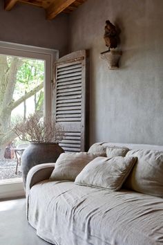 a white couch sitting in front of a window next to a wooden ceiling mounted headboard