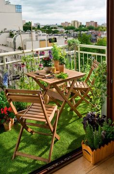 a balcony with chairs, table and potted plants on the grass in front of an open window