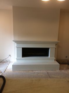 an empty living room with a fireplace in the middle and no one around it on the floor