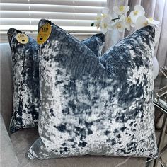 two blue and white pillows sitting on top of a couch