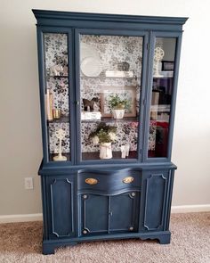 a blue china cabinet with glass doors and drawers