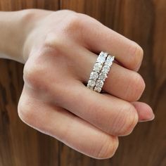 a woman's hand holding an engagement ring with three rows of diamonds on it