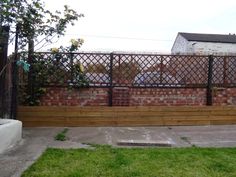 a wooden bench sitting in front of a fenced area with green grass on the ground