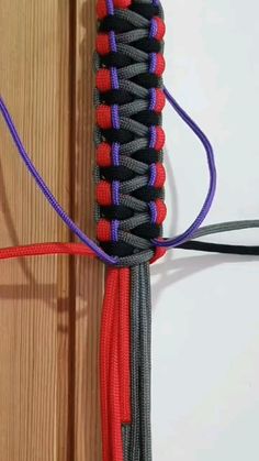 a red, black and blue cord connected to a wooden wall