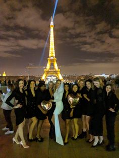 a group of women posing in front of the eiffel tower