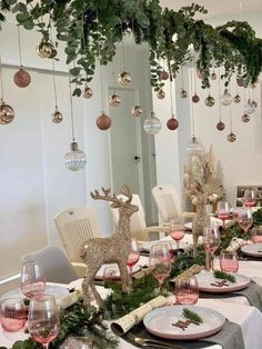 the table is set for christmas dinner with ornaments hanging from the ceiling and deer figurines