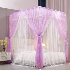 a pink canopy bed with sheer curtains and lights