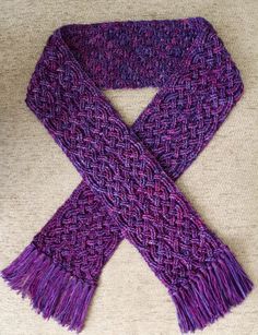 a purple knitted scarf laying on top of a couch