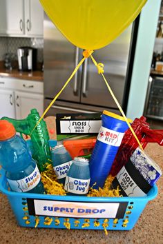 a blue basket filled with lots of different items on top of a counter next to a refrigerator