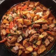 a pan filled with potatoes and carrots sitting on top of a stove burner