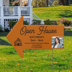 an orange open house sign in front of a lawn with flowers and trees on it