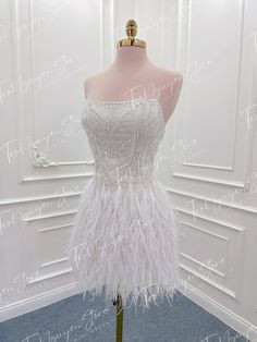 a mannequin wearing a white dress with feathers on it