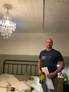 a man standing in front of a bed with construction materials on the floor next to him