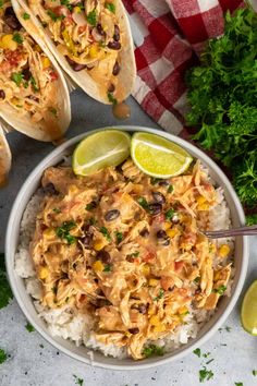 two tacos with chicken, black beans and corn on rice in a white bowl