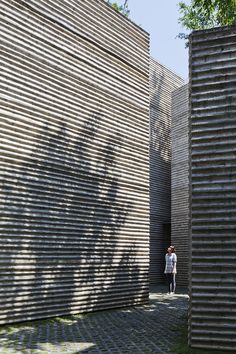 two people are standing in front of some large wooden structures with shadows on the wall