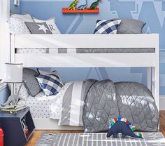 a child's bedroom with blue walls and white bunk beds, dinosaur toys on the floor