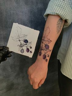 a person with a tattoo on their arm holding a piece of paper