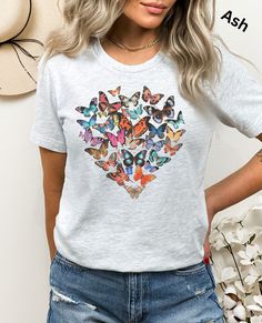 Wear Your Hope: Butterfly Heart T-Shirt ✨ This stunning t-shirt features a trendy and inspirational design of a heart formed by a vibrant collage of butterflies. Each butterfly boasts beautiful colors and unique patterns, symbolizing the strength found in diversity and the overcoming of challenges. This isn't just a shirt, it's a powerful statement.  It's a reminder to yourself or a loved one that hope and beauty can emerge even after facing difficulties. It's the perfect motivational gift for a Trendy Short Sleeve T-shirt With Butterfly Print, Trendy Butterfly Print Crew Neck Tops, Trendy Crew Neck Tops With Butterfly Print, Spring Heart Print Crew Neck T-shirt, Gray Tops With Sublimation Print For Summer, Summer Heart-shaped Letter Print T-shirt, Spring Heart Graphic Tee, Spring Heart-shaped Graphic Tee, Multicolor Heart Print Crew Neck Top