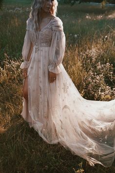 a woman wearing a white dress standing in the grass