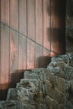 a cat sitting on top of a stone wall next to a wooden door and window