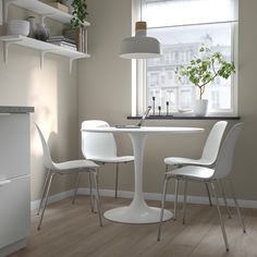 a white table and chairs in front of a window with a potted plant on it