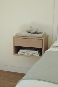 a nightstand with two books on it next to a bed