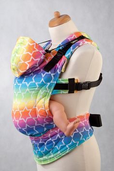 a baby wearing a colorful sling on top of a mannequin