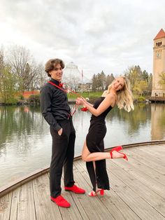 two people standing on a dock with one holding the other's leg and posing for a photo