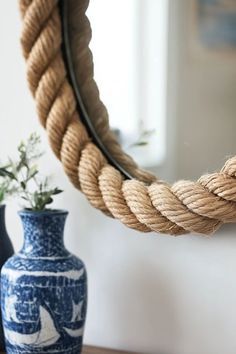 a blue and white vase sitting next to a rope mirror